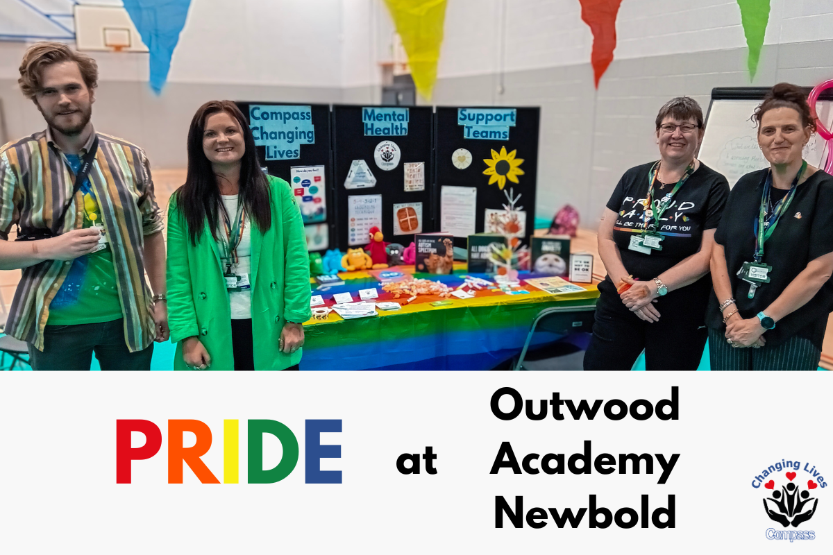 Pride at Outwood Academy Newbold. A group of Changing Lives staff stand smiling next to a stand bedecked with rainbow colours.