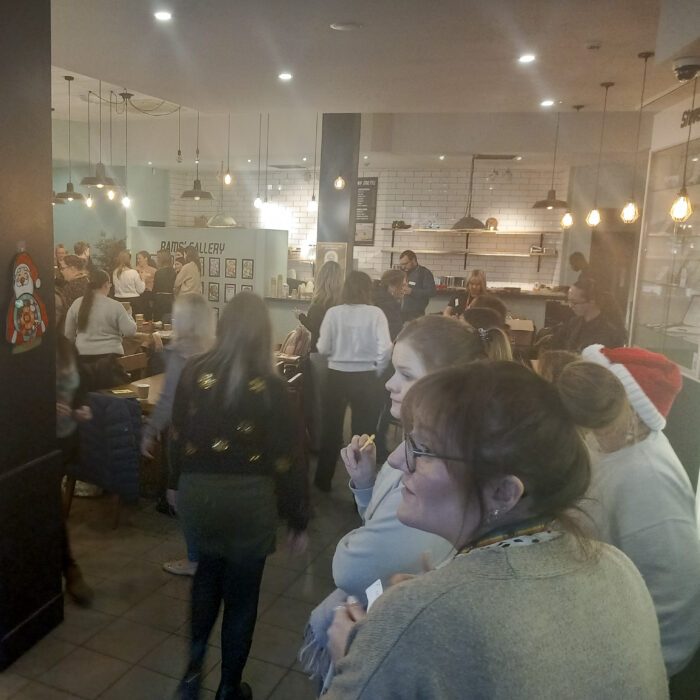 This image shows a group of people gathered in a restaurant. They are all wearing festive attire and seem to be enjoying each other's company. There are people talking, eating, and drinking. The atmosphere looks warm and inviting.