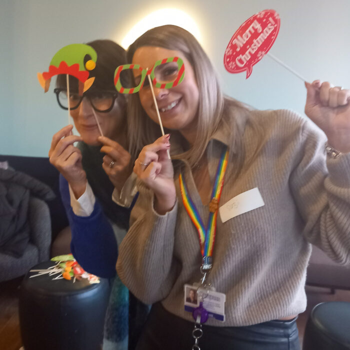 This image shows two women posing for a photo with festive props. They are both smiling and enjoying themselves.