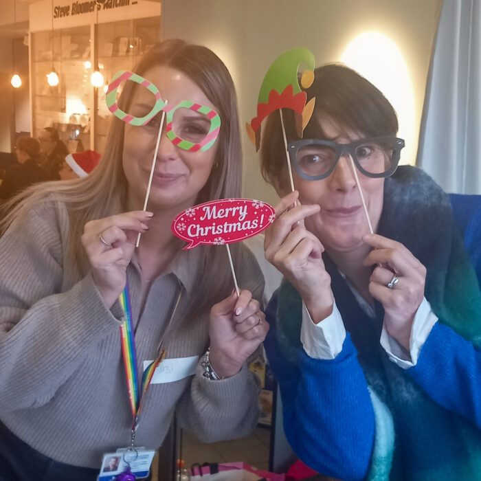 This image shows two women posing for a photo with festive props. They are both smiling and enjoying themselves.