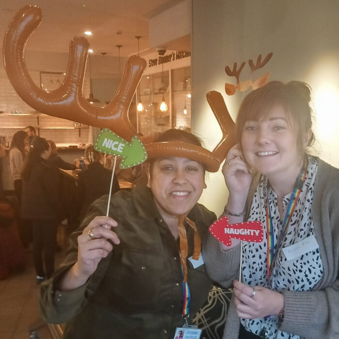 This image shows two women posing for a photo with festive props. They are both smiling and enjoying themselves.